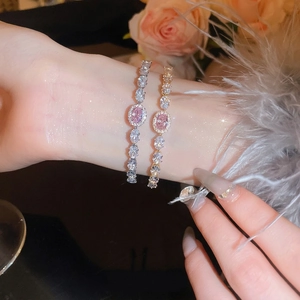 Gold and silver bracelets with pink oval stones and zircons worn on a wrist