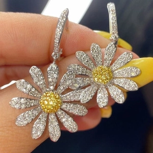 Macro shot of silver daisy earrings with yellow heart-shaped zircons and pavé diamonds