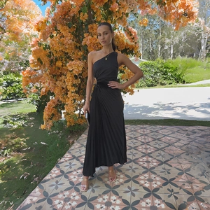 Detail of elegant black one-shoulder dress with side cutout and pleated texture on the waist