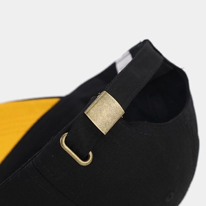 Detail of adjustable black fabric strap with vintage copper metal buckle on baseball cap
