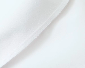 Detailed macro view of white fabric texture and reinforced edge stitching on skirt pants