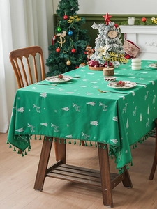 Detail of forest green Christmas tablecloth with white reindeer motifs and fringe edges