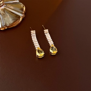 Detailed view of long gold drop earrings featuring yellow pear-cut and clear crystals