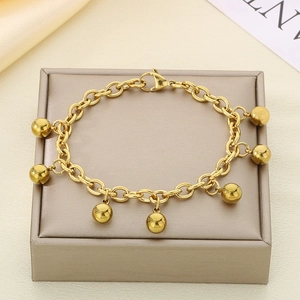 Macro detail of 18K gold plated steel bracelet with ball pendants on a jewelry box