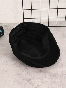 Detail view of the black suede newsboy cap interior showing stitching and adjustable snaps