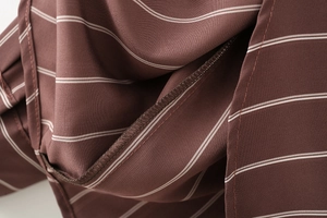 Macro shot of vertical white stripes on brown fabric with high-quality hem stitching details