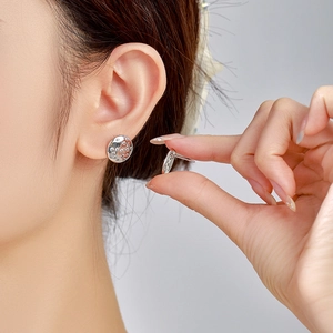 Macro shot of silver circular earrings with textured surface and pavé zircon stones