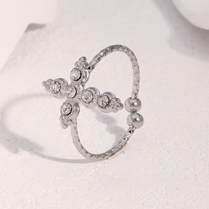 Détail macro d'une bague croix argentée avec cristaux brillants et texture martelée