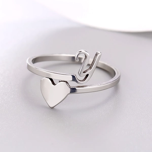 Macro shot of silver letter Y and solid heart charm on stainless steel open ring