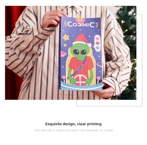 Detail of purple Christmas paper gift bag with cosmic alien and festive holiday graphics