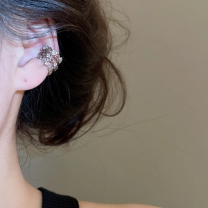 Detail of elegant gold-tone multi-layered ear cuff with sparkling zircon on model ear