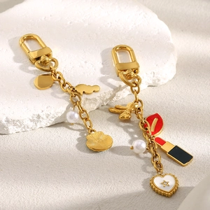 Détail de breloques dorées 18K avec rouge à lèvres rouge et papillon en émail