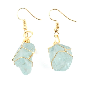Macro detail of handmade light blue raw stone earrings with gold wire wrapped design
