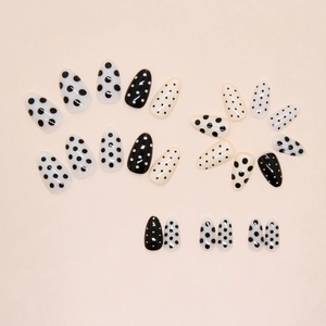 Chic almond press on nails with cream and black polka dot patterns in a glossy finish