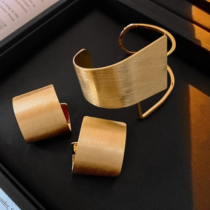 Macro detail of gold-plated brushed metal jewelry set showing fine horizontal textures