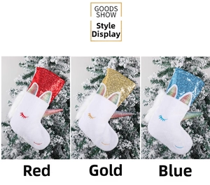 Three sequined unicorn Christmas stockings in red, gold, and blue on a snowy background