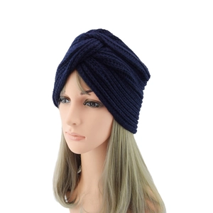 Close-up of deep blue knitted turban hat with thick bohemian cross knot design