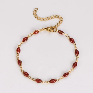 Detail of a gold stainless steel bracelet with oval red glitter resin charms and clasp