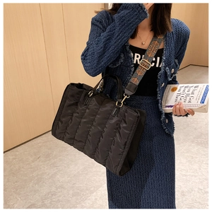 Detail of black quilted nylon tote bag with ethnic style wide strap and handles