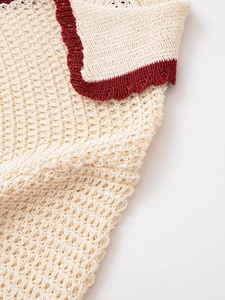 Detailed macro view of cream knit fabric with contrasting deep red piped edges