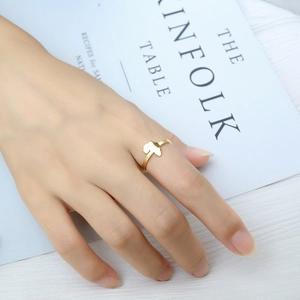 Fashionable golden heart-shaped open ring shown on a model hand with Kinfolk lifestyle props
