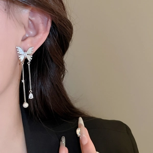 Detail of silver butterfly earring with tassel chain, pearl, and zircon teardrop on ear