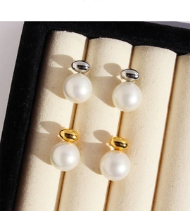 Macro view of gold and silver pearl stud earrings in a luxury velvet jewelry display box