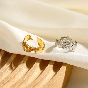 Detailed view of gold and silver feather rings on white silk over a wooden tray
