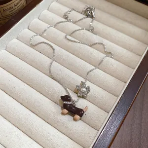 Collier en argent avec pendentif teckel marron et fleur de perle sur boîte à bijoux beige