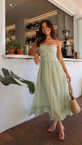 Détail d'une robe d'été vert clair avec buste à volants et bretelles fines à lacets