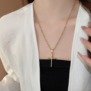 Close-up of a layered 18k gold-plated cross pendant necklace on a female model