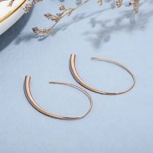 Minimalist rose gold water drop earrings on blue background with floral shadows