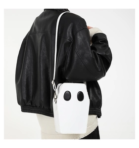Macro view of coffin-shaped white shoulder bag featuring creative black leather appliques