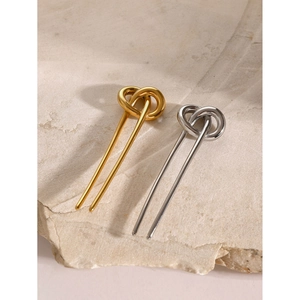 Polished stainless steel pretzel knot hair pins in gold and silver on a beige stone base