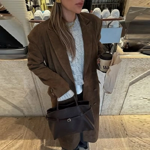 Détail d'un manteau long en daim marron avec un design à double boutonnage et col à revers