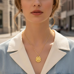 Close-up of golden coin necklace with eagle relief on model in natural outdoor light