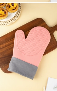 Detailed view of pink silicone heat-resistant oven glove with non-slip texture on wood
