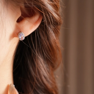 Macro detail of oval light purple zircon earring with sparkling crystal halo on ear
