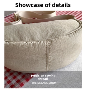 Detail of precise stitching on the bottom of a beige nylon dumpling crossbody bag