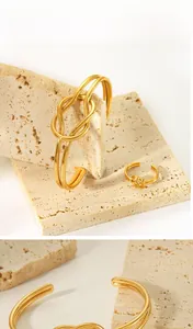 Detail eines 18K vergoldeten Knotendesign-Rings und Armreifs auf Steinhintergrund