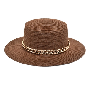 Détail du chapeau de paille marron avec une grosse chaîne dorée en acrylique