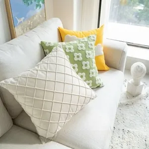 Detail of embroidered textured throw pillows in cream, green and yellow on a sofa