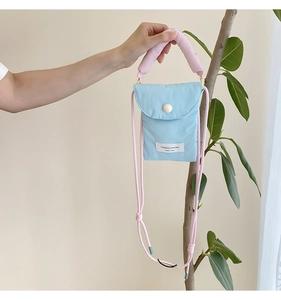 Detail of blue padded phone pouch with pink handle and white original design woven label
