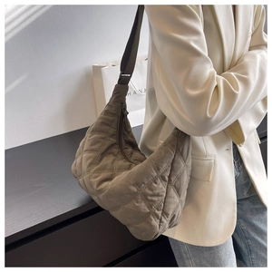 Close-up of a women's taupe quilted crossbody bag with adjustable strap on a model