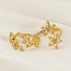 Detailed close-up of golden leaf and flower rings with sparkling zircon on silk