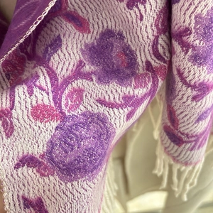 Close-up of bohemian floral jacquard pattern and fringe details on a knit shawl