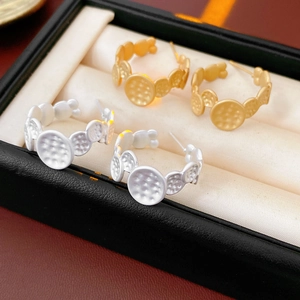 Détail de boucles d'oreilles créoles en C avec texture martelée en or et argent