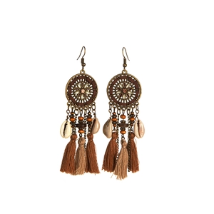 Detailed shot of Bohemian long tassel earrings with brown feathers and shell beads