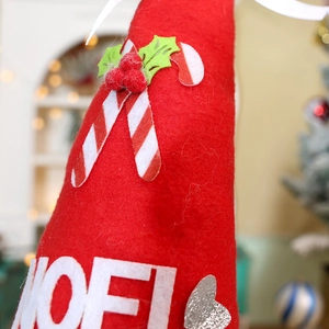 Close-up of red felt Christmas gnome decoration with white NOEL lettering and holly details