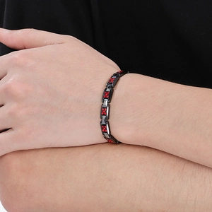 Gros plan d'un bracelet en acier tungstène noir avec strass rouges sur un poignet